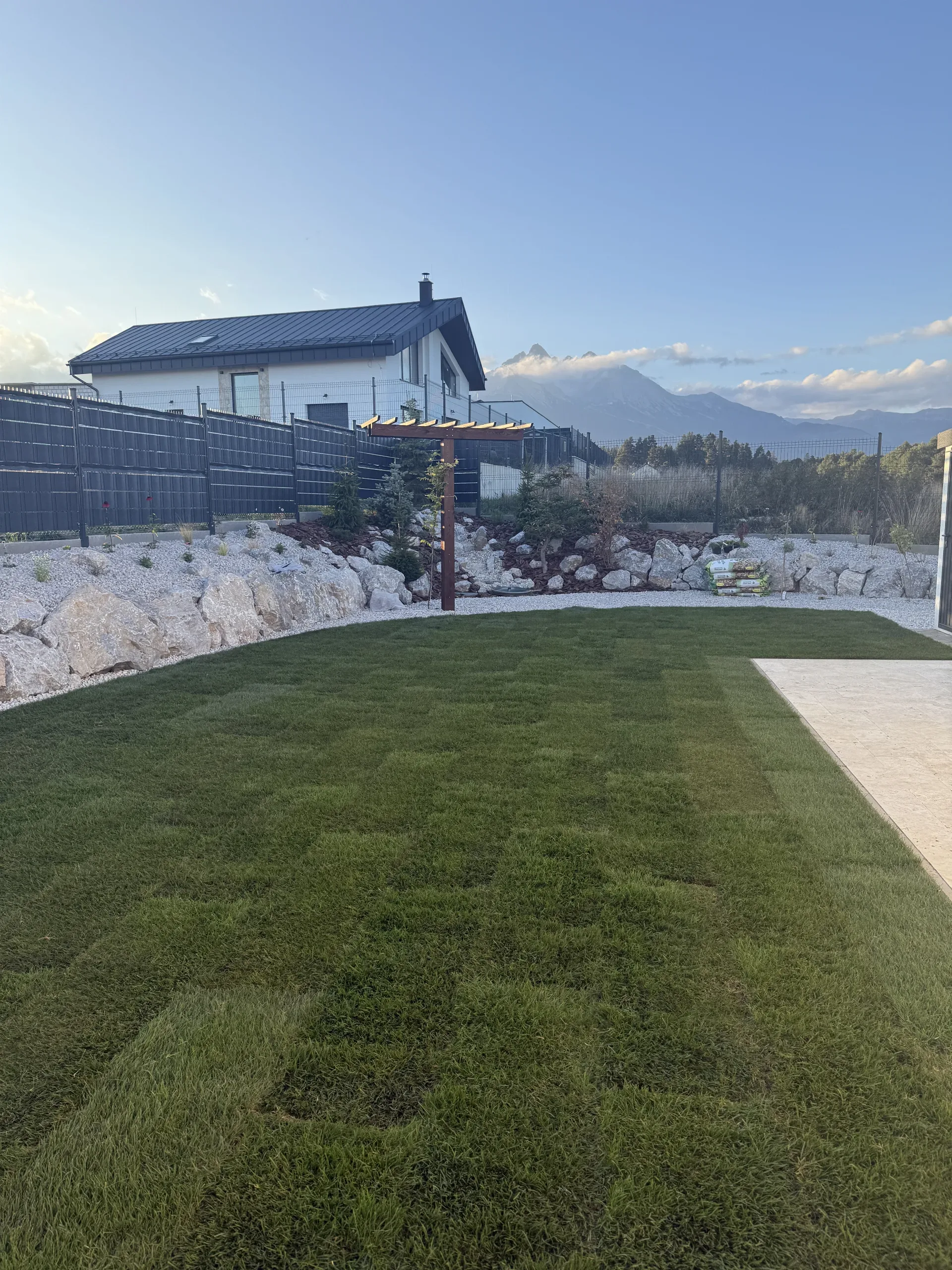 Nový trávnik so skalkou pozdĺž plota, v pozadí Tatry