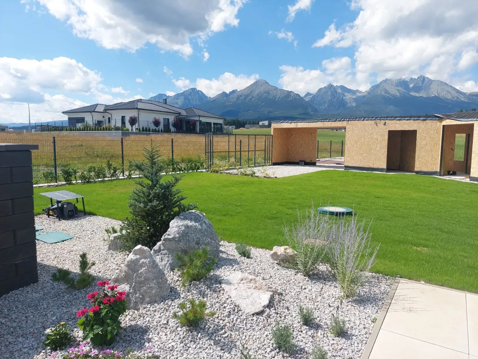Hotová záhrada so skalkou a trávnikom, v pozadí Tatry